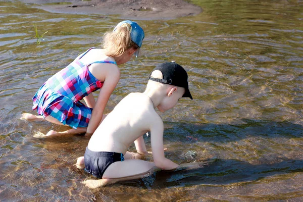 Мальчик и девочка играют на пляже в воде, пляжный семейный отдых у реки — стоковое фото