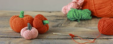 Cadılar Bayramı için ahşap bir arka planda örülmüş iplikten yapılmış turuncu, pembe balkabağı, bayram için DIY dekoru.