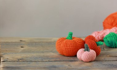 Cadılar Bayramı için ahşap bir arka planda örülmüş iplikten yapılmış turuncu, pembe balkabağı, bayram için DIY dekoru.