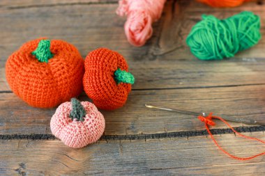 Cadılar Bayramı için ahşap bir arka planda örülmüş iplikten yapılmış turuncu, pembe balkabağı, bayram için DIY dekoru.