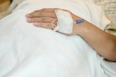 Hastane yatağında yatan erkek hastanın ellerine odaklan. Enjeksiyon için hazır olun ya da damardan ilaç verin..