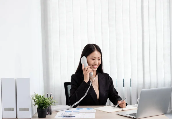 オフィスで働いている間 アジアのビジネスマンは電話で話し 明るく幸せな笑顔でラップトップで働いています — ストック写真