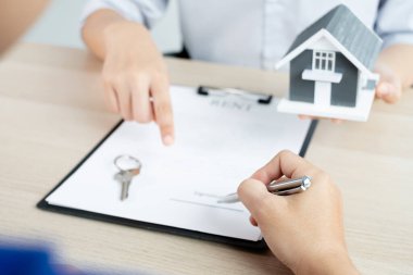 Kiralık evleri olan bir emlakçı ve müşteriler için ev kiralama sözleşmesi imzalayan bir emlakçı. Ev kiralama ve sigorta konsepti.