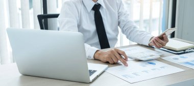 İş adamı masalarında oturur ve başarılı iş büyümesi sürecini planlayan yatırımlarının sonuçlarını gösteren mali grafikleri hesaplar.