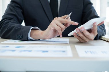 İş adamı masalarında oturur ve başarılı iş büyümesi sürecini planlayan yatırımlarının sonuçlarını gösteren mali grafikleri hesaplar.