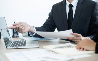 İki iş lideri çizelgeler, finansal grafikler hakkında konuşuyor. Sonuçları gösteren planlama stratejilerini analiz ediyor ve hesaplıyor. Ticari başarı oluşturma süreçlerini de..