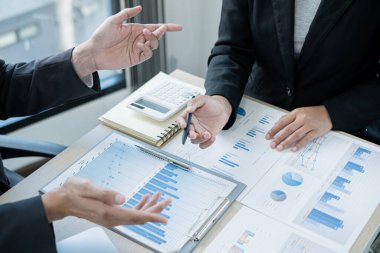 İki iş lideri çizelgeler, finansal grafikler hakkında konuşuyor. Sonuçları gösteren planlama stratejilerini analiz ediyor ve hesaplıyor. Ticari başarı oluşturma süreçlerini de..