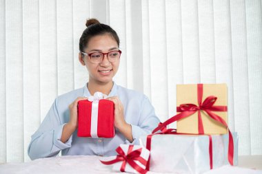 Asyalı kadın bir hediye kutusu tutuyor. Bayramlarda, Noel 'de, doğum günlerinde ya da Sevgililer Günü konseptinde sürpriz yapmaktan mutluluk duyuyor..