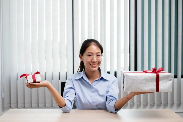 Asian woman holding a gift box Glad to be the giver of surprise with excitement, joy and smiles on the holidays, Christmas, birthdays or Valentine\'s Day concept.