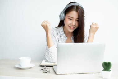 Video çağrısı, kulaklık takan genç bir Asyalı kadın, internetteki uzun mesafeli video ile iletişim kuruyor, dijital laptop ekranına bakıyor, bir arkadaşıyla mutlu bir şekilde selamlaşıyor..