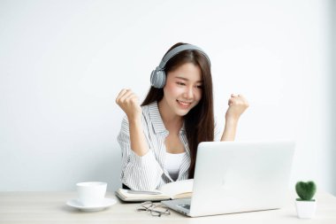 Video çağrısı, kulaklık takan genç bir Asyalı kadın, internetteki uzun mesafeli video ile iletişim kuruyor, dijital laptop ekranına bakıyor, bir arkadaşıyla mutlu bir şekilde selamlaşıyor..