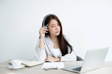 Video çağrısı, kulaklık takan genç bir Asyalı kadın, internetteki uzun mesafeli video ile iletişim kuruyor, dijital laptop ekranına bakıyor, bir arkadaşıyla mutlu bir şekilde selamlaşıyor..