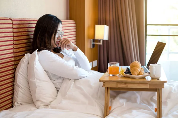 아시아의 여성들은 프리랜서 하면서 행복하게 웃으면서 방에서 스낵과 과일로 침대에서 — 스톡 사진