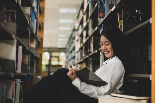 Young Asian women are searching for books and reading books on the tables and aisles of the college libraries to research and develop their academic and education self.