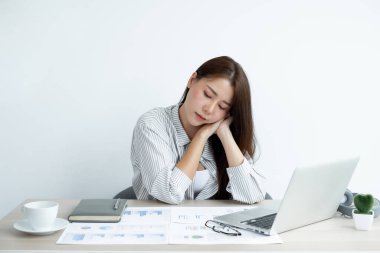 Çalışan Asyalı kadınlar stresli, işten yorgun, ofiste çalışırken çok çalışmaktan migren ağrısı çekiyor..
