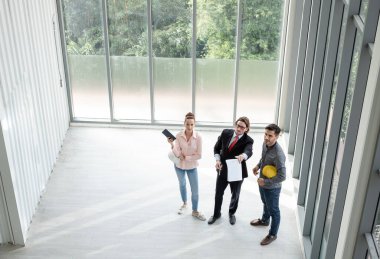 Erkek ve kadın mühendisler ve mimarlardan oluşan bir ekip, çalışma ekibi, inşaat planlarını tartışıyor ve çiziyor, baskı yapıyor, inşaat alanlarında yazıyor. Üst görünüm.