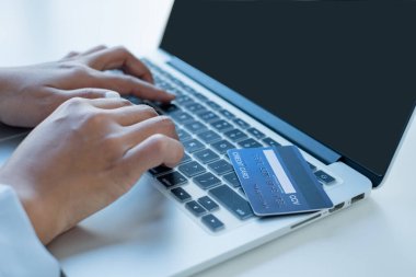 İş kadınının eli bir kredi kartı tutuyor ve online alışveriş ve internet ödemeleri için dizüstü bilgisayar kullanıyor.