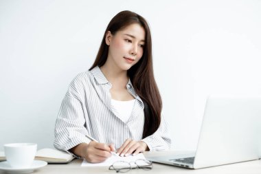 Asyalı kız üniversite öğrencileri evde ders çalışıyor, ekstra dersler alıyor, videolar izliyor ve dijital bir laptoptan not alıyor, evde bir masada otururken ekrana bakarak ödev yapıyor..