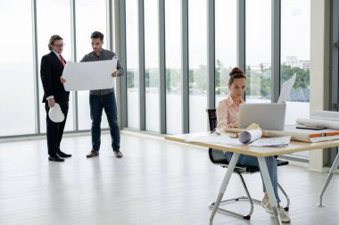 Erkek ve kadın mühendisler ve mimarlardan oluşan bir ekip, çalışma ekibi, inşaat planlarını tartışıyor ve çiziyor, baskı yapıyor, inşaat alanlarında yazıyor..