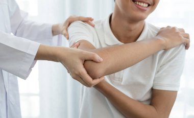 Kadın fizyoterapistler, dirsek yaralanması olan erkek hastalara rehabilitasyon merkezlerindeki hastaları muayene etmede yardımcı oluyorlar. Rehabilitasyon fizyoterapi konsepti.