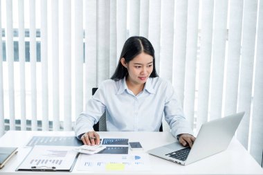 Asyalı kadın muhasebeci masalarında oturup yatırımlarıyla ilgili sonuçları gösteren mali grafikleri hesaplar ve başarılı bir iş büyüme süreci planlar..