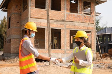 Tokalaşın, erkek ve kadın mühendisler veya mimarlardan oluşan ekip açık hava inşaat çalışmalarını inceliyor ve inceliyor..