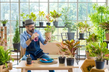 Yaşlı bir adamın bıyıklı olması bitkileriyle ilgilenmekten, sulamaktan, ilaçlamaktan ve bitkileri dekore etmekten zevk alır. Evde bahçecilik hobisi, emeklilikten sonra mutlu yaşamak..