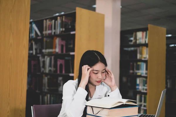 Young Asian women are searching for books and reading books on the tables and aisles of the college libraries to research and develop their academic and education self.