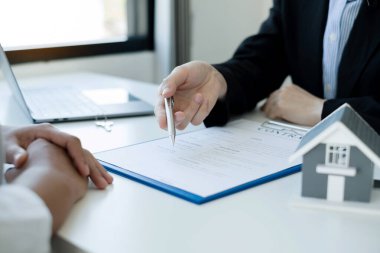 Ev modeli olan bir emlakçı ev sigortası almak için müşterilerle konuşuyor. Ev sigortası kavramı.