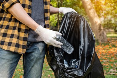 Adamın elleri plastik şişeleri topluyor, çöpleri siyah çöp torbalarına doldurup parkları temizliyor, kirlilikten kaçınıyor, çevreye ve ekosisteme dost oluyor..