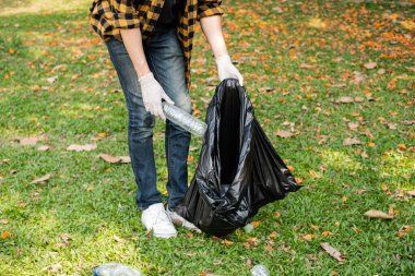 Adamın elleri plastik şişeleri topluyor, çöpleri siyah çöp torbalarına doldurup parkları temizliyor, kirlilikten kaçınıyor, çevreye ve ekosisteme dost oluyor..