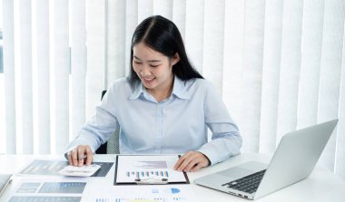 Asyalı kadın muhasebeci masalarında oturup yatırımlarıyla ilgili sonuçları gösteren mali grafikleri hesaplar ve başarılı bir iş büyüme süreci planlar..