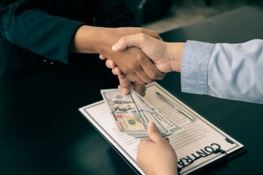 Yozlaşma. İş adamları para ile bir anlaşma yaptılar. Ortağına ofiste rüşvet teklif etti ve anlaşma altında bir sözleşme yaptı. Yasadışı para dolandırıcılığı Rüşvet ve yolsuzluk kavramı.