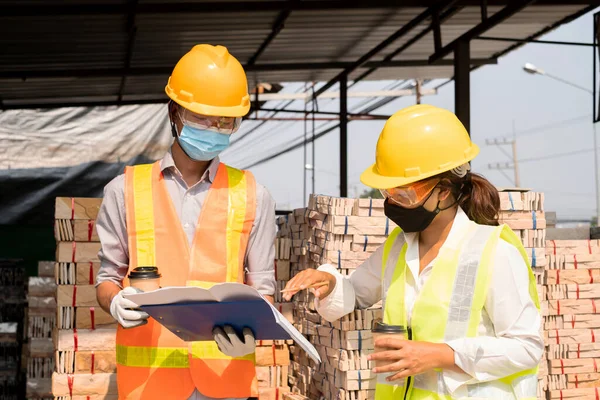 A team of male and female engineers or architects is exploring and inspecting the outdoor construction site work.