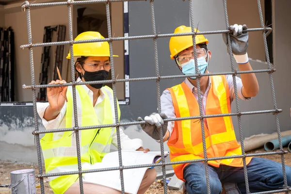 A team of male and female engineers or architects is exploring and inspecting the outdoor construction site work.
