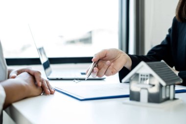 Ev modeli olan bir emlakçı ev sigortası almak için müşterilerle konuşuyor. Ev sigortası kavramı.