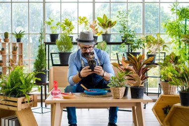 Bıyıklı, yaşlı ve yakışıklı bir adam ağaç bakımıyla mutlu olur. Evde bahçıvanlık hobisi. Emeklilikten sonra mutlu yaşamak. Doğa ve çevre kavramları.