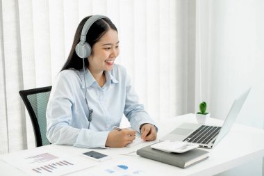 Bilgisayarda çalışan Asyalı kadın. Başarılı gülümseyen iş kadını ofiste çalışıyor ve not alıyor..