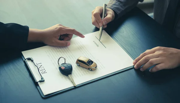 The car dealer provides advice on loans, insurance details, and car rental information, and delivers the car with the keys after the rental contract is signed.