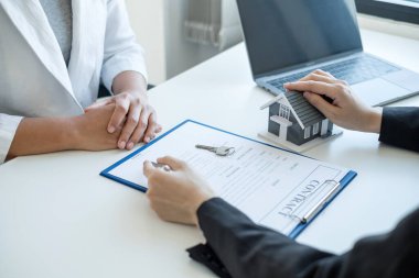 Ev modeli olan bir emlakçı ev sigortası almak için müşterilerle konuşuyor. Ev sigortası kavramı.