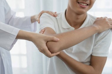 Kadın fizyoterapistler, dirsek yaralanması olan erkek hastalara rehabilitasyon merkezlerindeki hastaları muayene etmede yardımcı oluyorlar. Rehabilitasyon fizyoterapi konsepti.