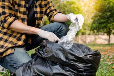 Adamın elleri plastik şişeleri topluyor, çöpleri siyah çöp torbalarına doldurup parkları temizliyor, kirlilikten kaçınıyor, çevreye ve ekosisteme dost oluyor..