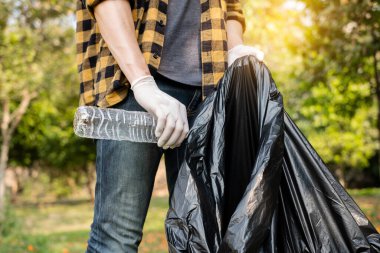 Adamın elleri plastik şişeleri topluyor, çöpleri siyah çöp torbalarına doldurup parkları temizliyor, kirlilikten kaçınıyor, çevreye ve ekosisteme dost oluyor..