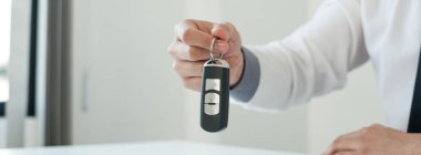 Araba satıcısı bir iş adamı arabanın anahtarını tutuyor. Araba kredisi ve sigorta konsepti.