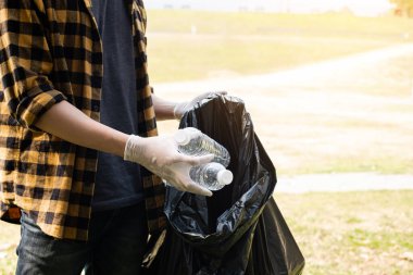Adamın elleri plastik şişeleri topluyor, çöpleri siyah çöp torbalarına doldurup parkları temizliyor, kirlilikten kaçınıyor, çevreye ve ekosisteme dost oluyor..