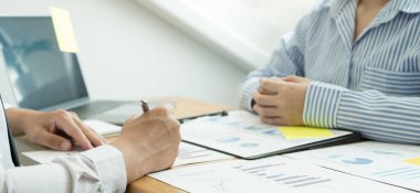 İki iş lideri çizelgeler, finansal grafikler hakkında konuşuyor. Sonuçları gösteren planlama stratejilerini analiz ediyor ve hesaplıyor. Ticari başarı oluşturma süreçlerini de..