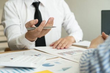 İki iş lideri çizelgeler, finansal grafikler hakkında konuşuyor. Sonuçları gösteren planlama stratejilerini analiz ediyor ve hesaplıyor. Ticari başarı oluşturma süreçlerini de..