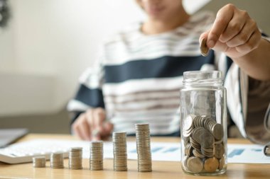 Kadın eli. Bozuk paralarla dolu bir cam şişeye bozuk para koy, bozuk paralarla para biriktir, başarılı bir büyüyen işe adım at ve emeklilikte düşünmek için para biriktir. Emeklilik tasarruf kavramı.