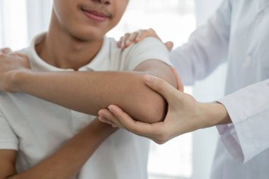 Kadın fizyoterapistler, dirsek yaralanması olan erkek hastalara rehabilitasyon merkezlerindeki hastaları muayene etmede yardımcı oluyorlar. Rehabilitasyon fizyoterapi konsepti.