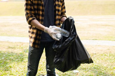 Adamın elleri plastik şişeleri topluyor, çöpleri siyah çöp torbalarına doldurup parkları temizliyor, kirlilikten kaçınıyor, çevreye ve ekosisteme dost oluyor..